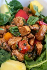 huli huli chicken salad in a bowl with greens