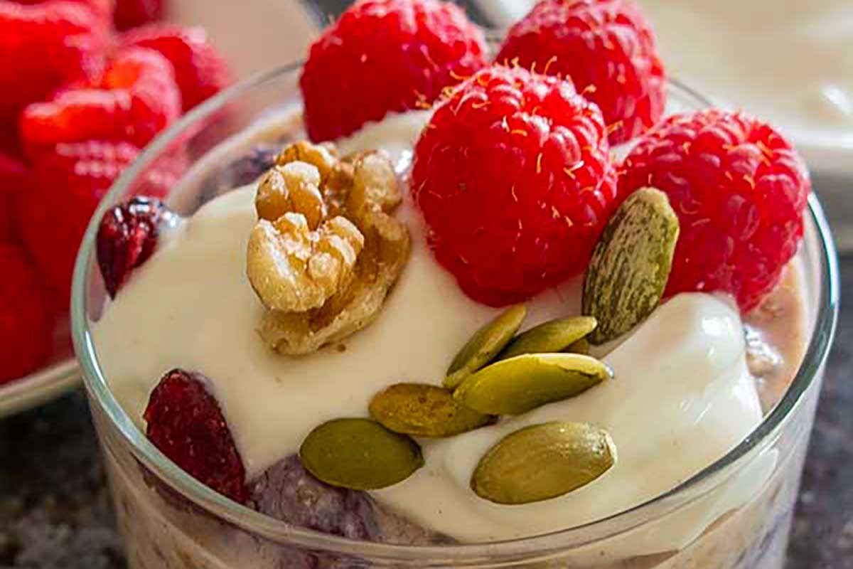 overnight oats topped with fresh fruit, nuts and seeds in a glass
