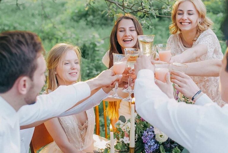 A joyful group cheers around a garden table, enjoying a festive summer dinner
