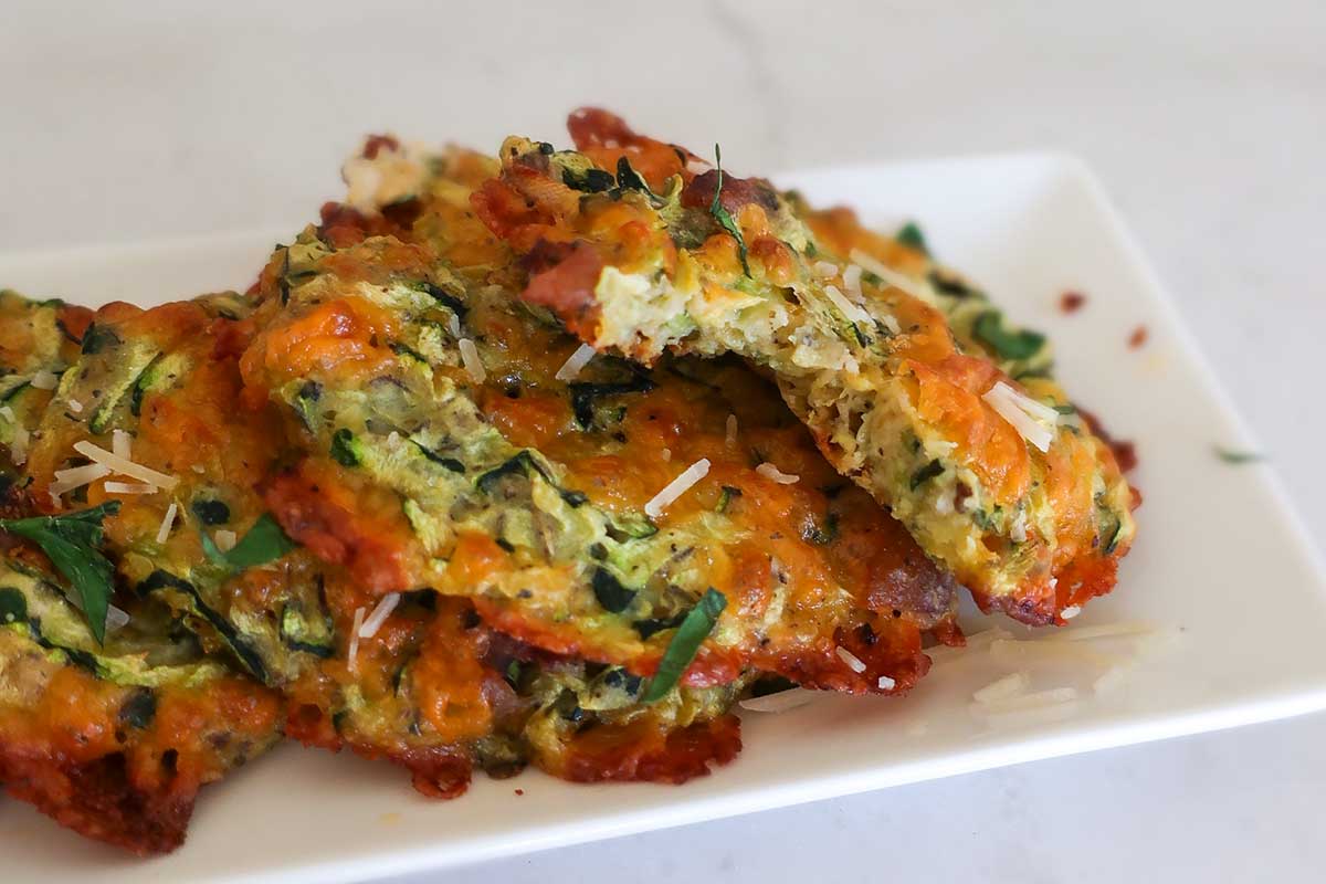 baked cheddar zucchini bars on a white plate toped with herbs