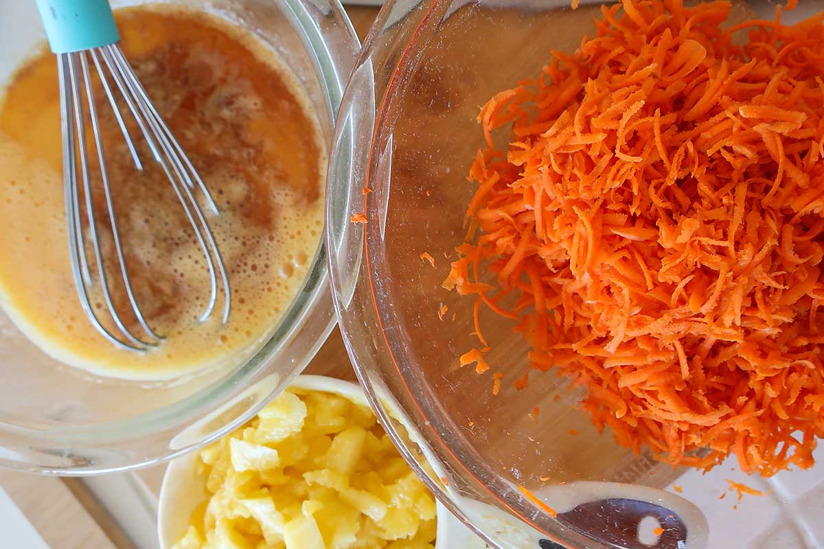 grated carrots, chopped pineapple, coconut oil with eggs and vanilla in 3 different bowls