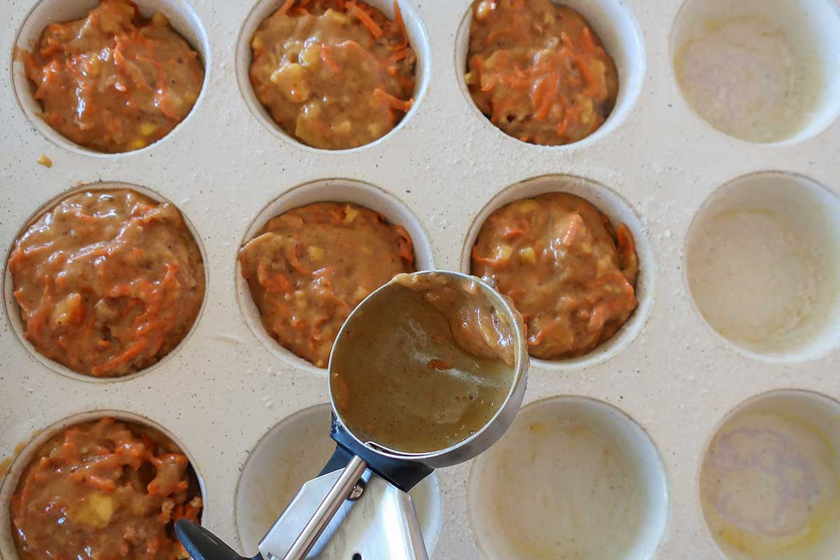 muffin pan partially filled with batter by using an ice cream scoop