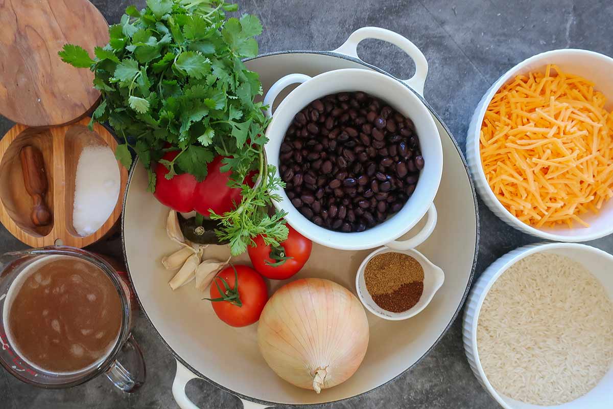 ingredients; black beans, rice, onion, bell pepper, garlic, cilantro, broth, spices, & cheddar in bowls