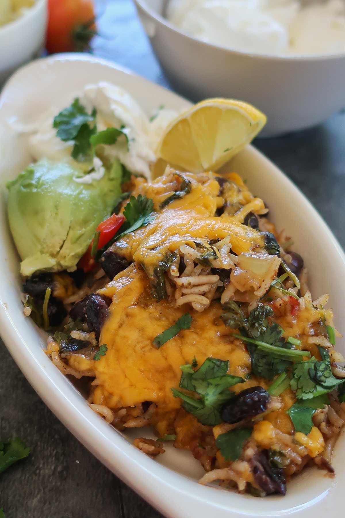A bright, close-up shot of a one-skillet no-tortilla veggie burrito bowl featuring melted cheddar cheese and chopped cilantro in a bowl