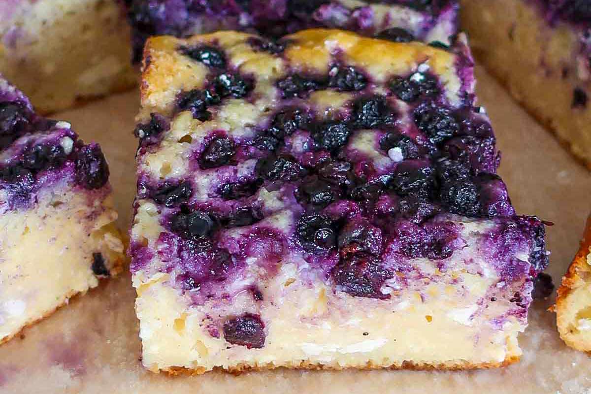 Close-up of a slice of Russian cottage cheese cake on a plate, packed with juicy blueberries and a creamy, tender texture.