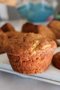 Close-up of a freshly baked Hawaiian-inspired muffin with golden crust, moist crumb, and bits of carrot and pineapple. Gluten and dairy-free tropical flavor