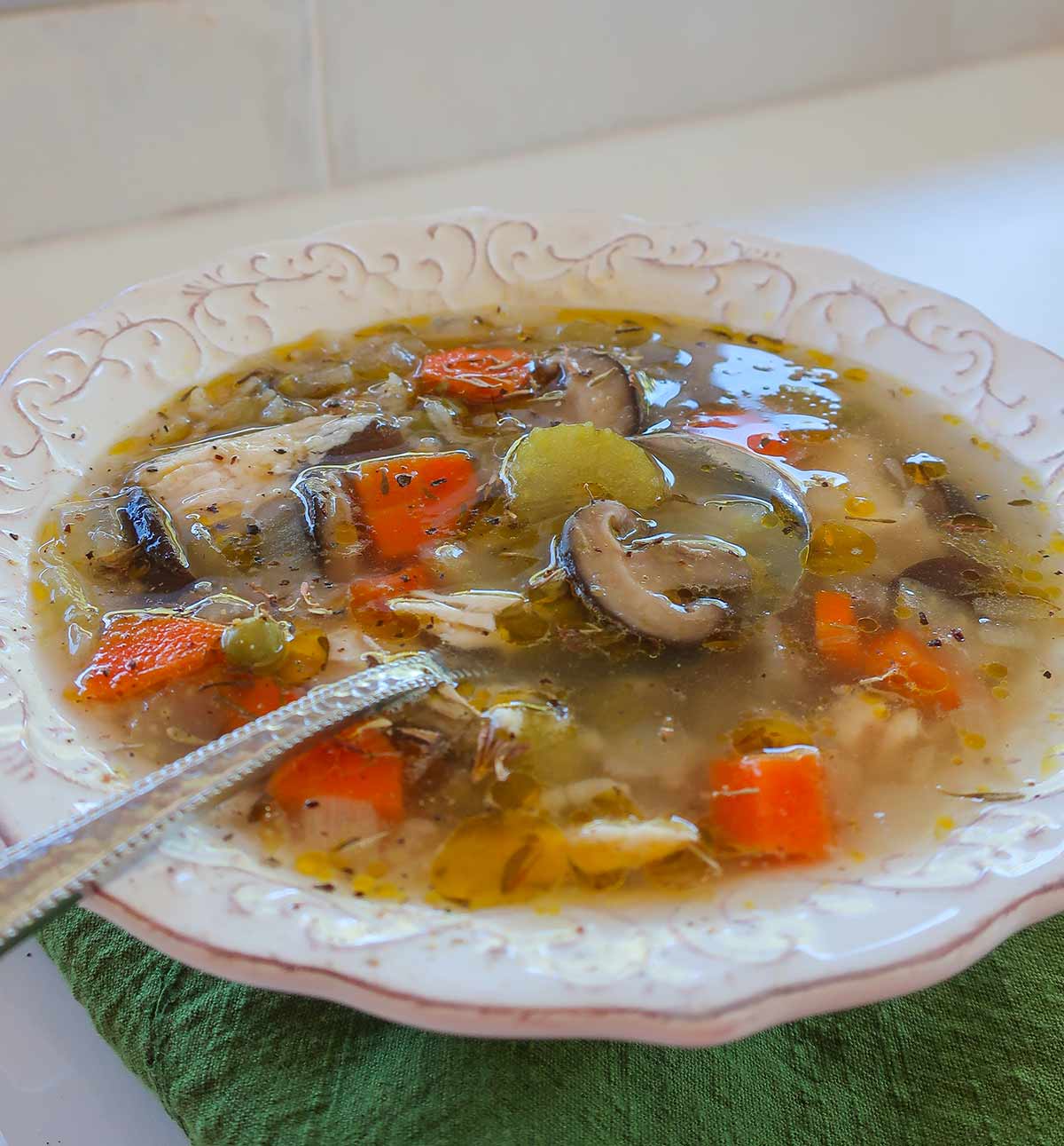 Close-up of chicken and rice soup with a spoon, showing tender chicken, rice, and colorful vegetables in broth.