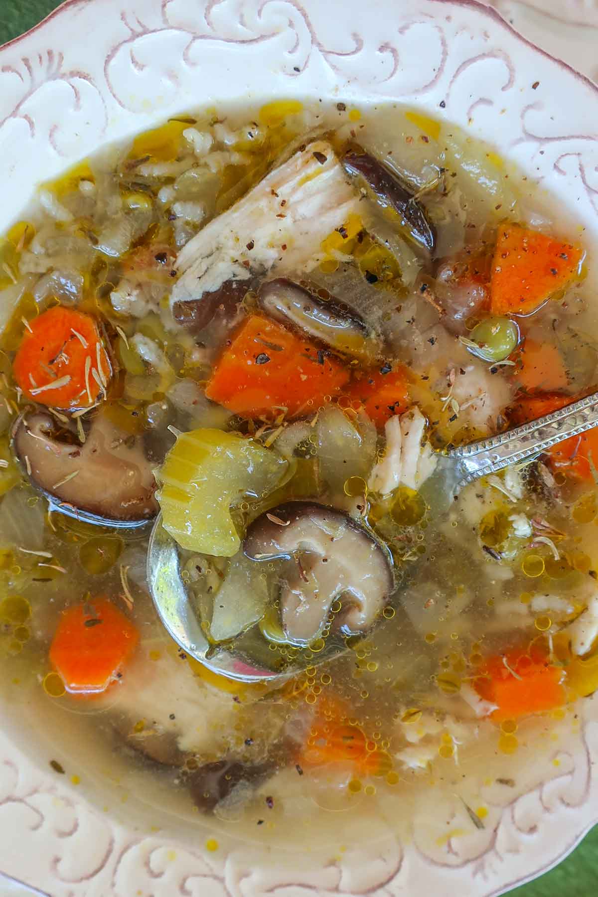 Overhead shot of a bowl of chicken and rice soup filled with vegetables and fresh herbs. 