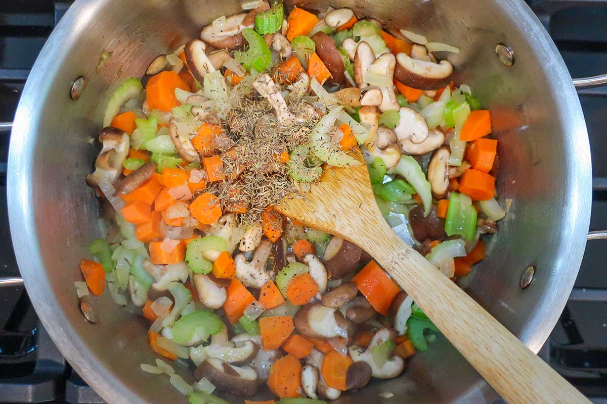 Chopped carrots, celery, onions, and mushrooms sautéing in a large soup pot with olive oil.