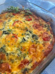 spinach cottage cheese bake in a pan topped with tomatoes and melted cheese