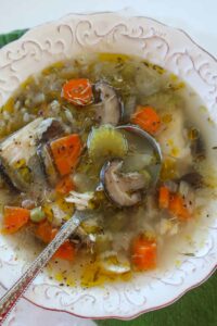 Close-up of chicken and rice soup with a spoon, showing tender chicken, rice, and colorful vegetables in broth.