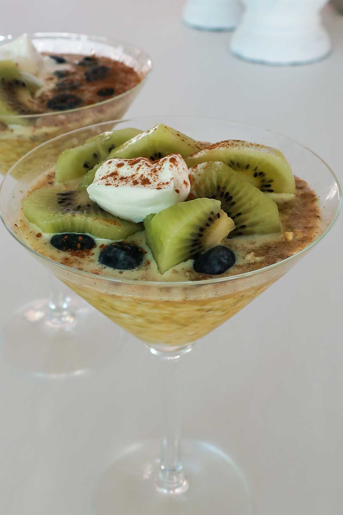 Gluten-free overnight oats with chia, psyllium, and turmeric, topped with yogurt and kiwi slices in a martini glass