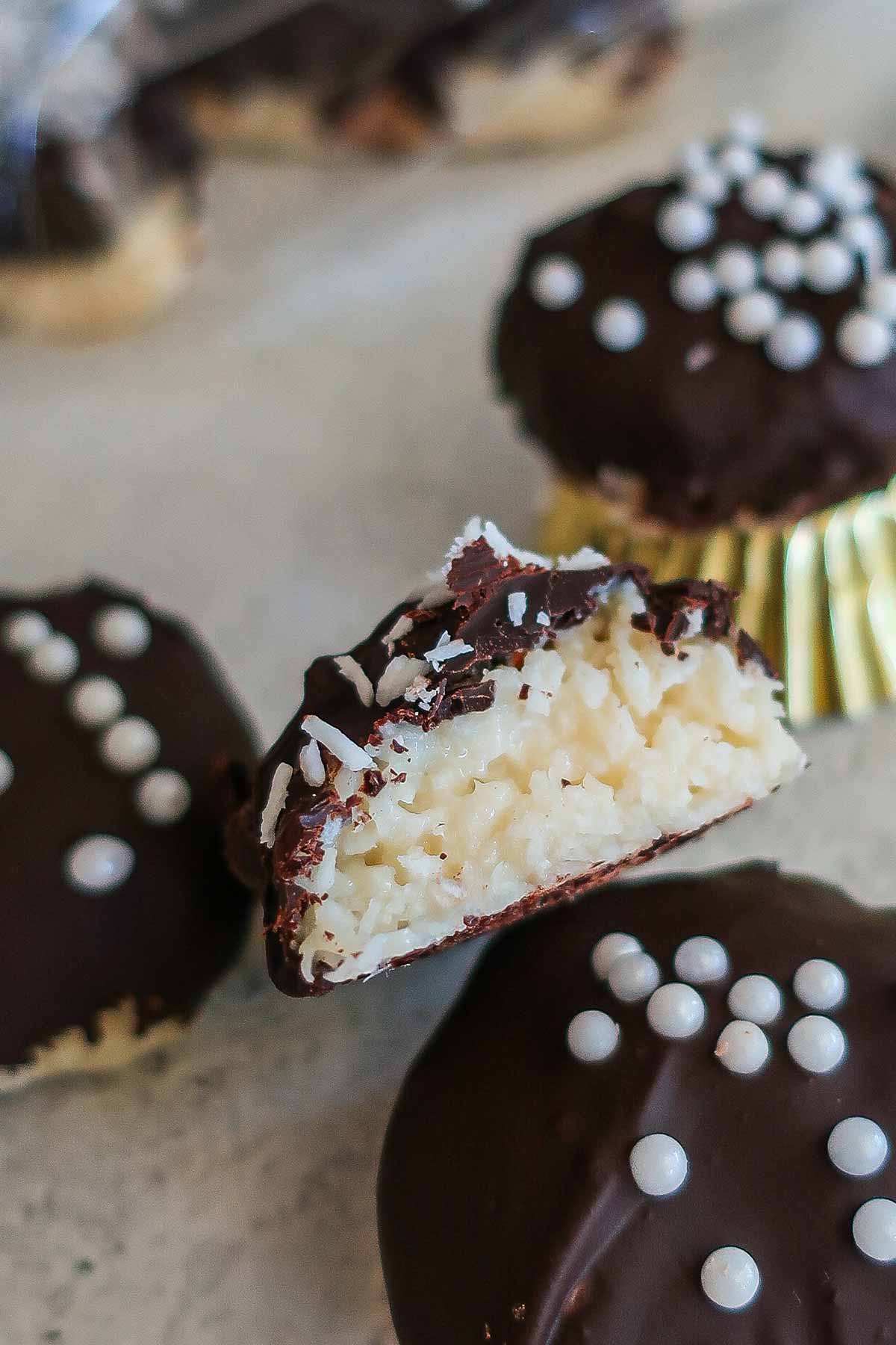 almond joy bars covered with chocolate and decorated with coconut, one showing creamy coconut inside