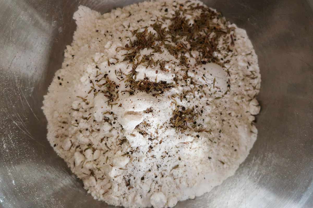 mixing flour, baking powder and soda, and herbs in a bowl