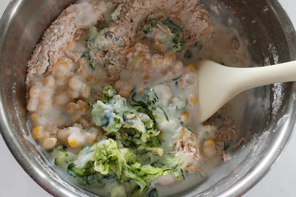 mixing dough for scones with zucchini, corn and buttermilk in a bowl