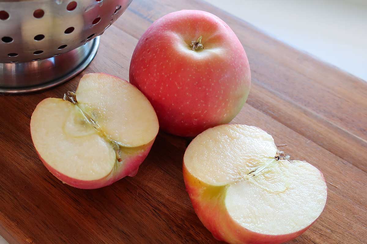 whole apple and a halve one on a cutting board for baking