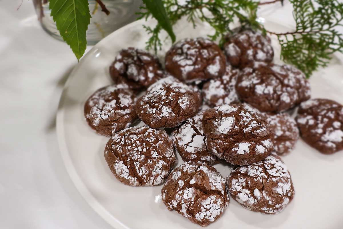 chocolate crinkle cookies coated with powdered sugar on a white platter