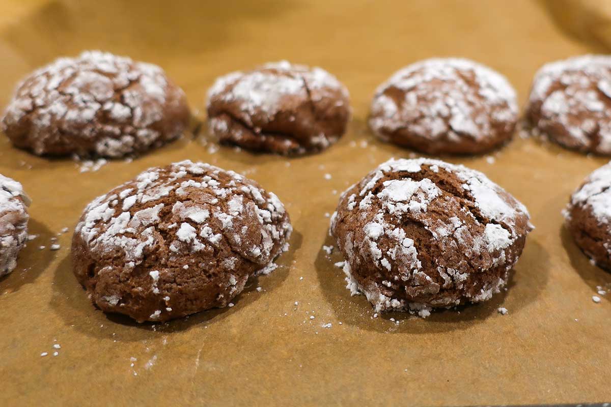 close up of freshly baked gluten free crinkle cookie on a baking sheet lined with parchment paper