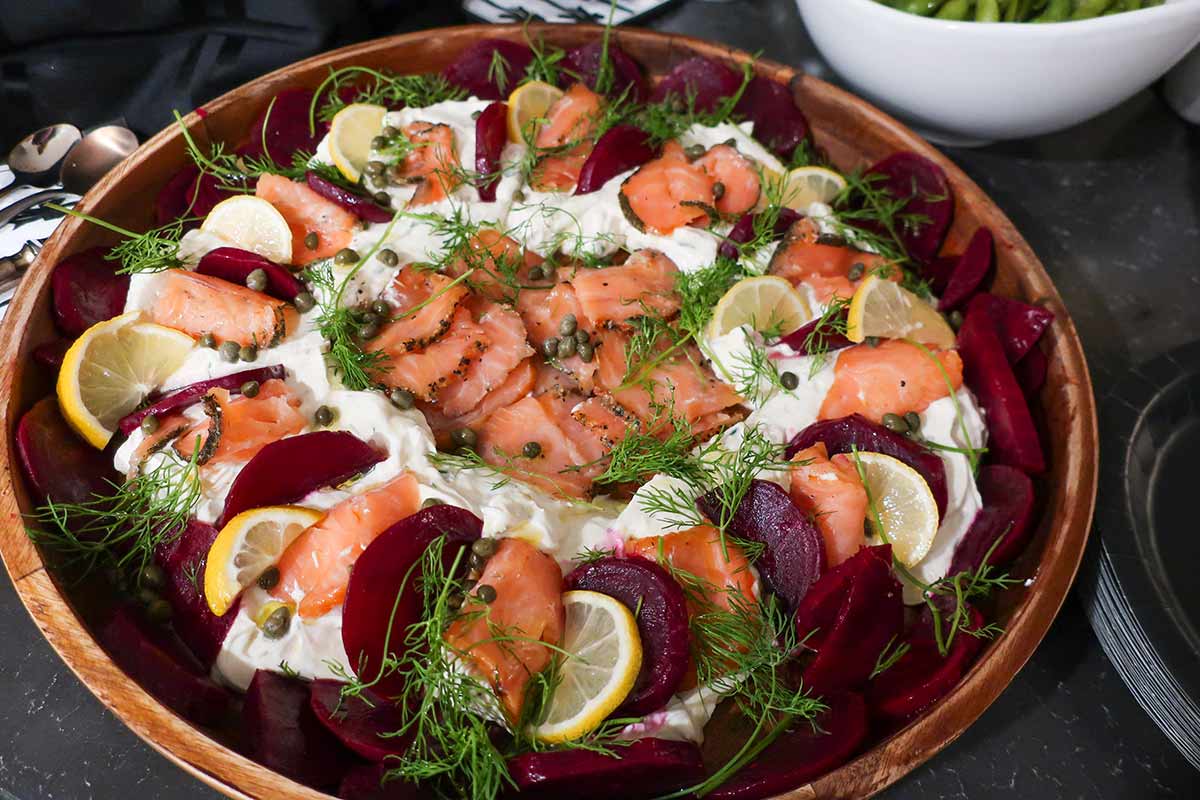 Scandinavian-style smoked salmon dip topped with roasted beets, fresh dill, and lemon slices on a serving platter — a colorful gluten-free appetizer.
