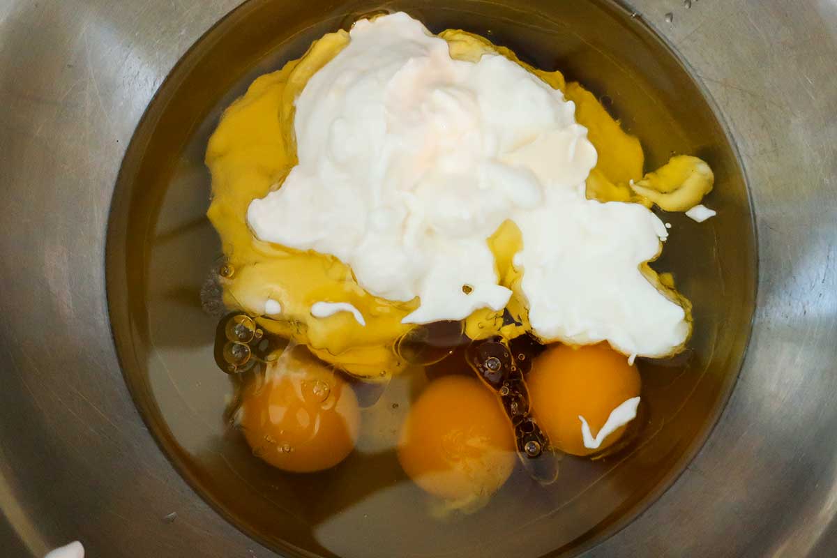 olive oil, sugar, eggs, salt, and Greek yogurt in bowl.