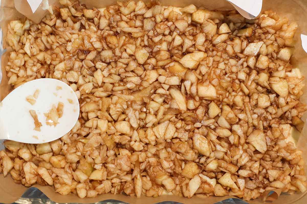 sweetened apple chunks spread over batter in a baking pan