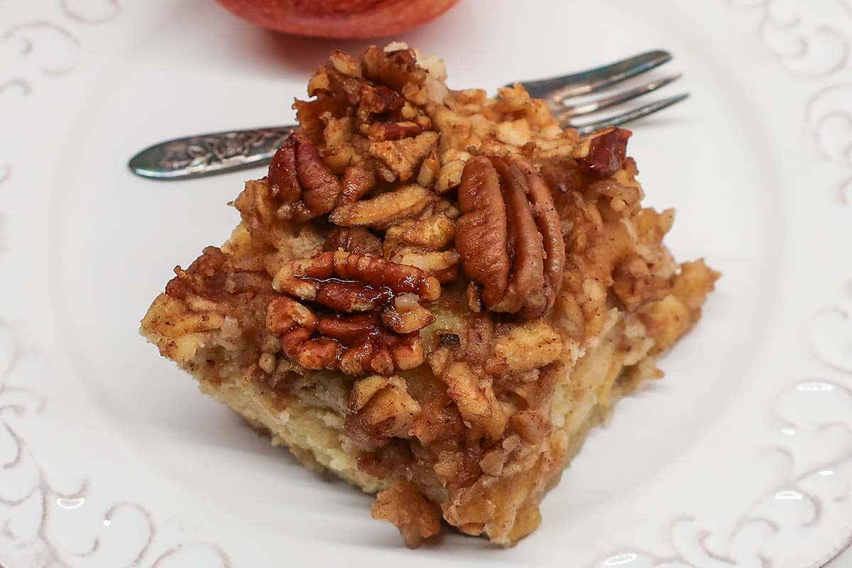top view of apple pecan yogurt cake on a plate with a fork showing candied pecans