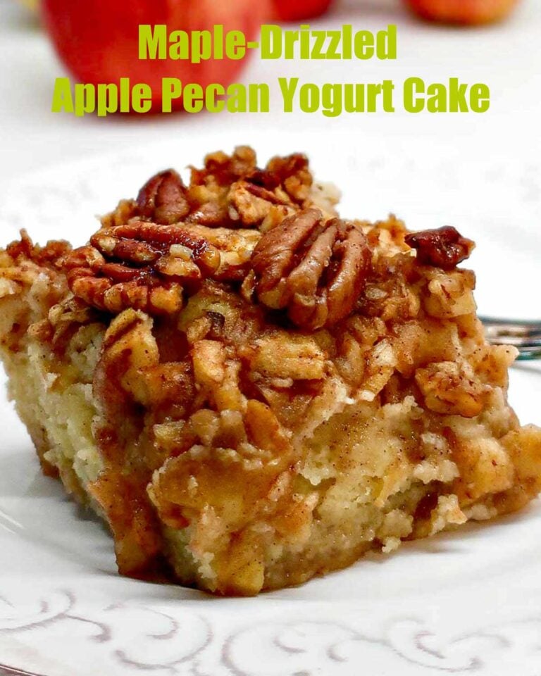 A thick slice of moist gluten-free apple pecan yogurt cake on a plate, featuring visible apple chunks, crunchy pecans, and a glistening maple drizzle