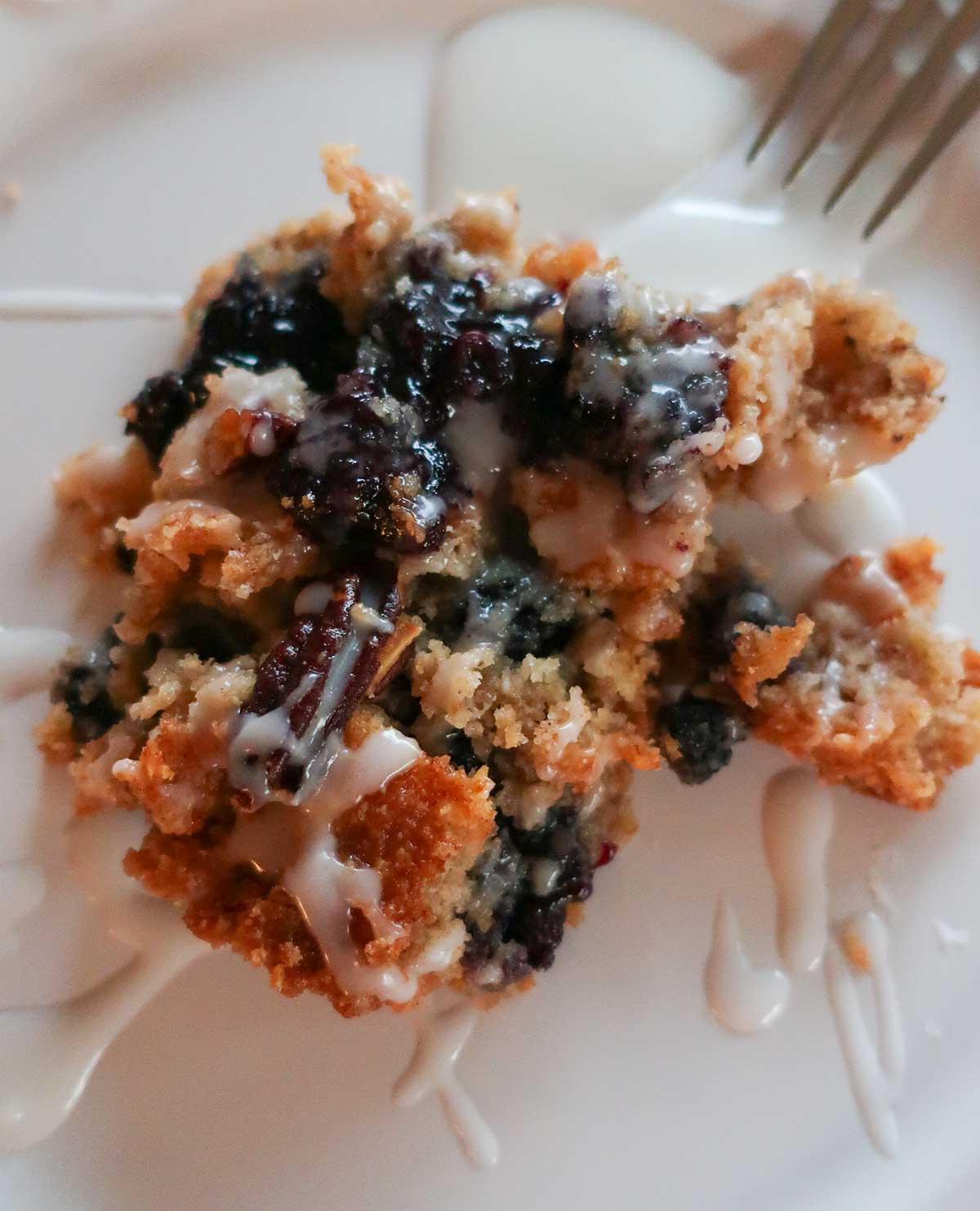 close up of one serving of blueberry dump cake showing blueberry filling & drizzled with lemon glaze