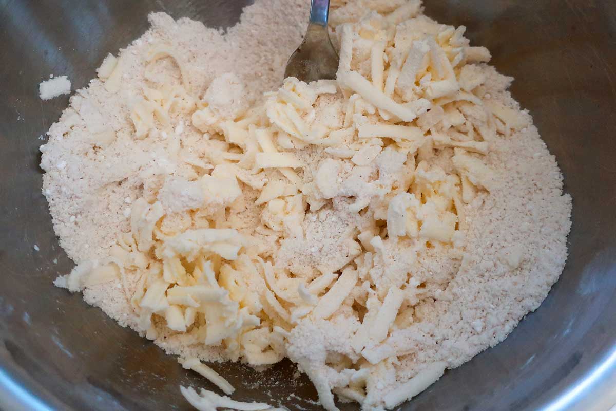 mixing dry ingredients with grated butter for the crust in a bowl