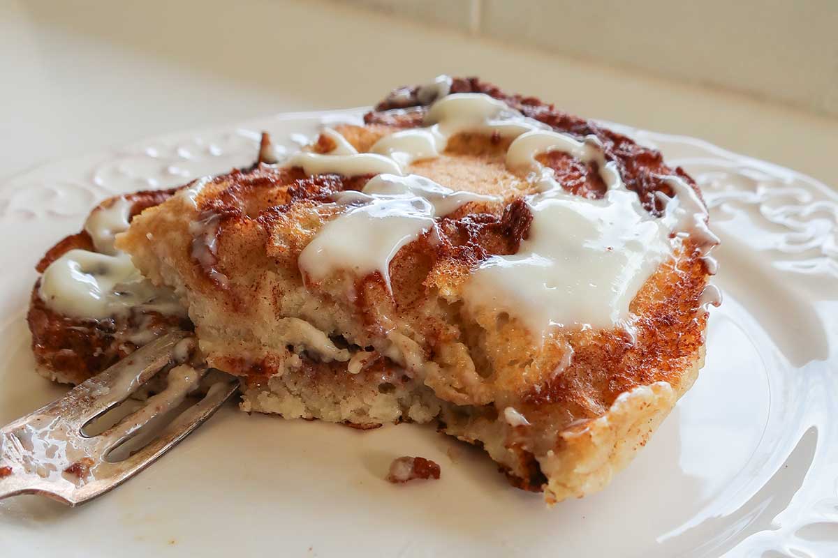 Dairy-free cream cheese frosting spread over half eaten stacked gluten-free pancakes