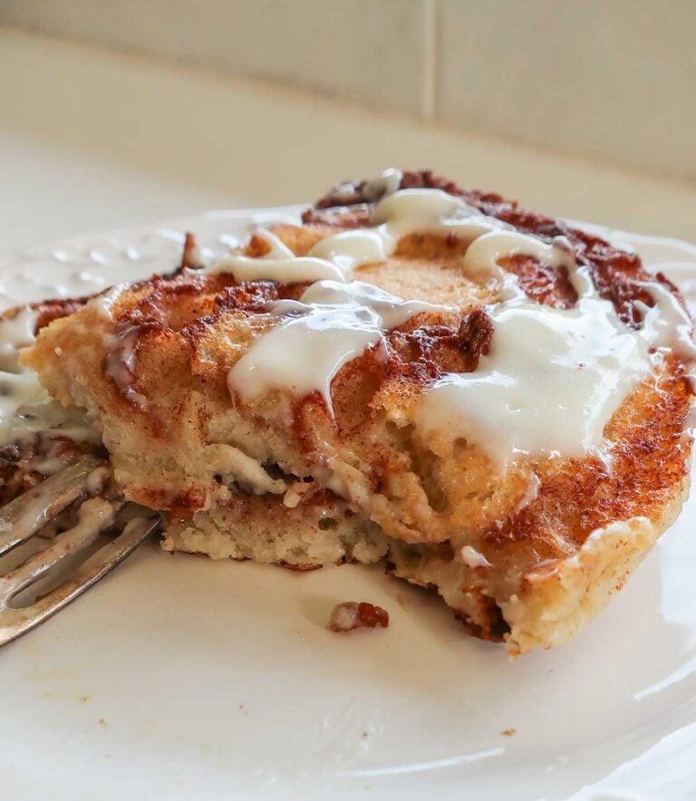 Dairy-free cream cheese frosting spread over stack of gluten-free vegan cinnamon roll pancakes