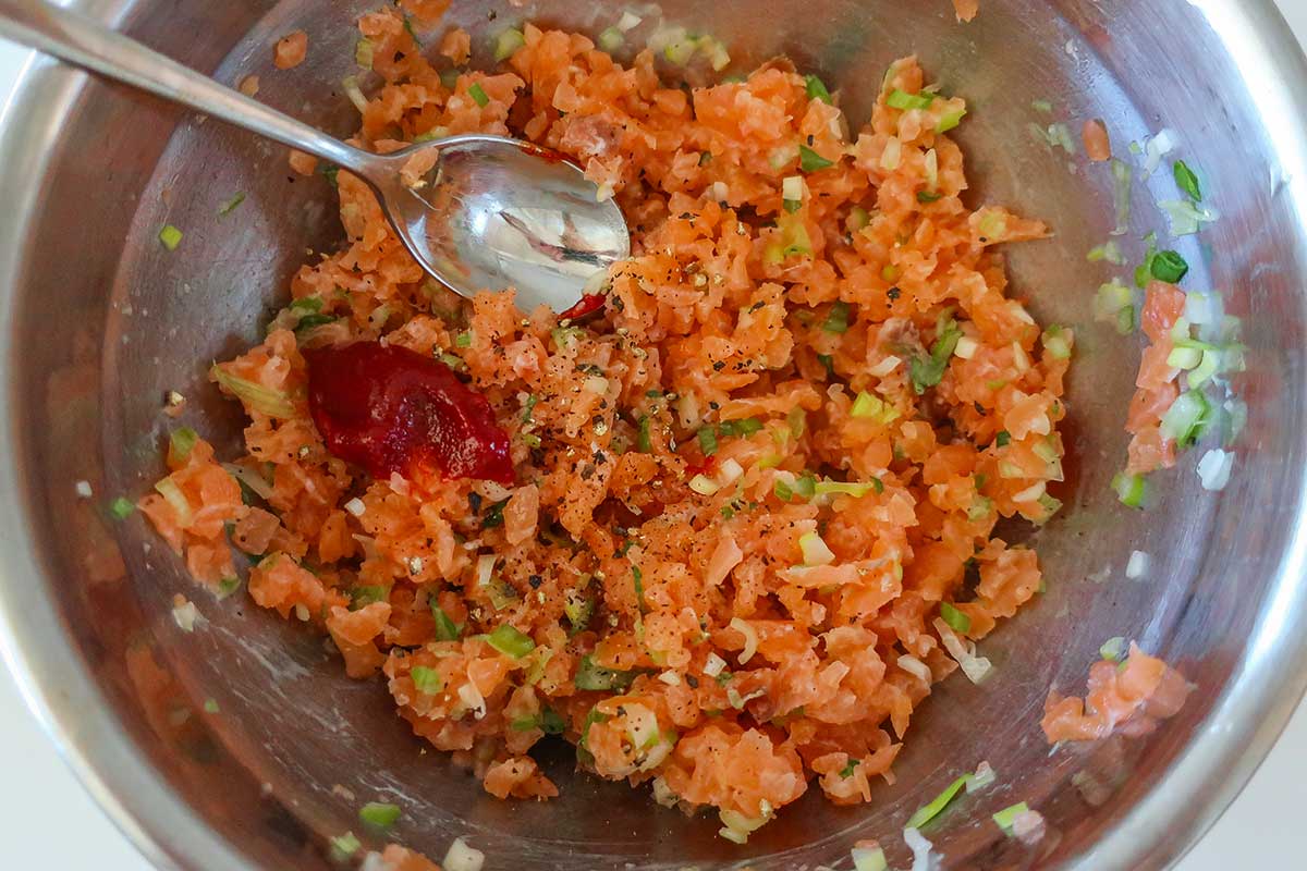 Smoked salmon mixed with green onions, gochujang paste, lemon juice, and black pepper in a bowl