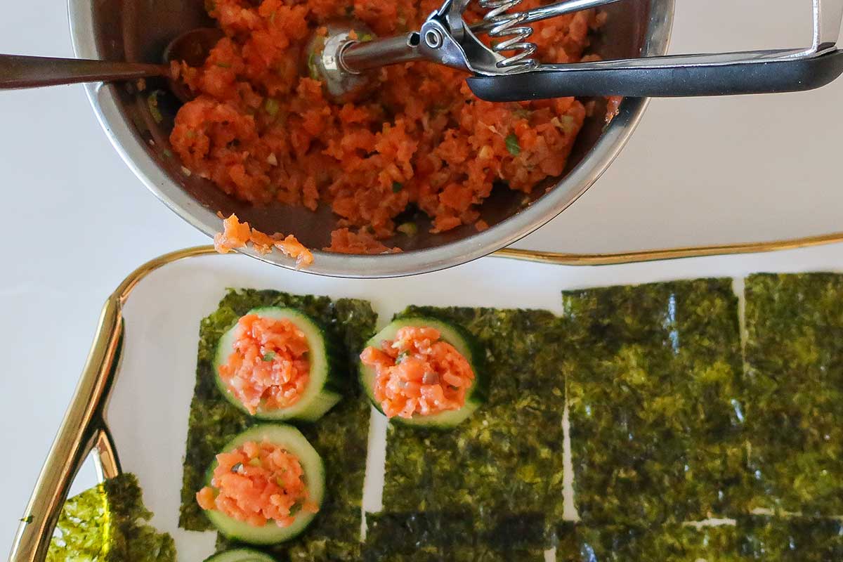 Gently pressing salmon mixture into hollowed cucumber slices