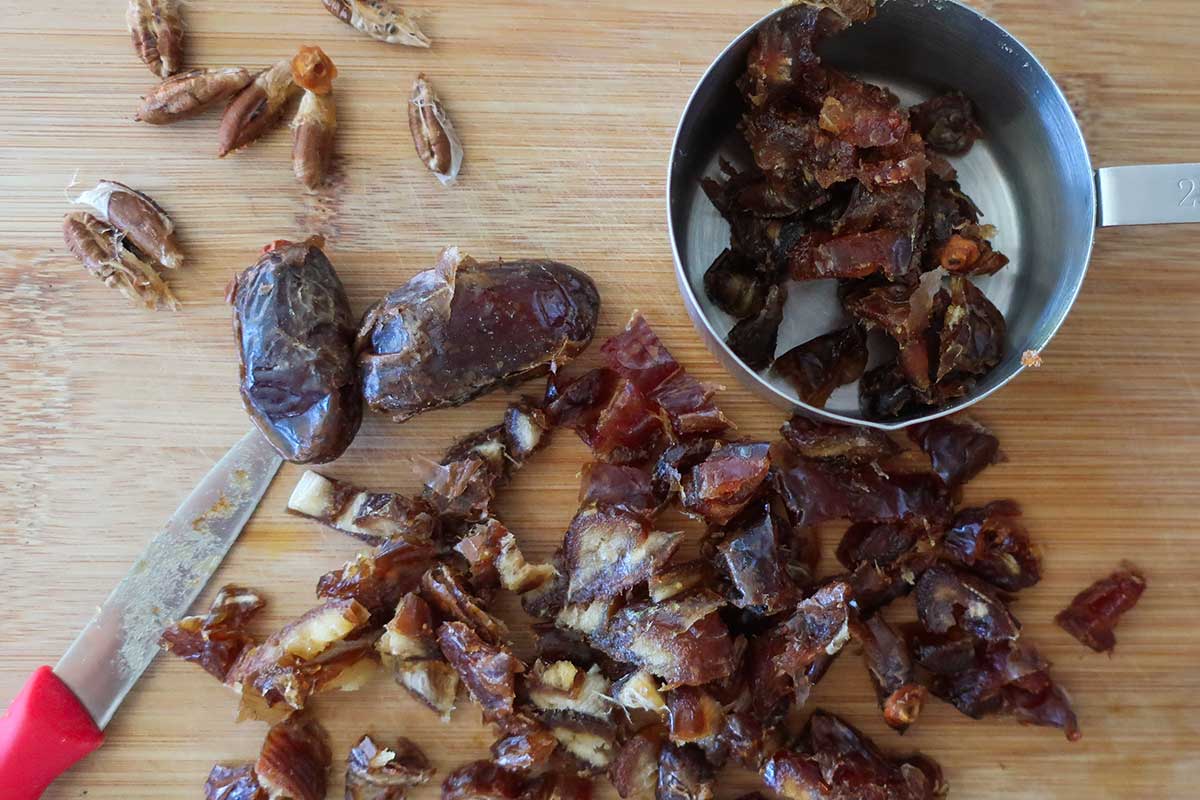 chopped dates on a cutting board with a measuring cup