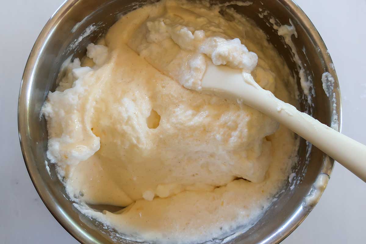 folding whipped egg whites into the batter in a bowl