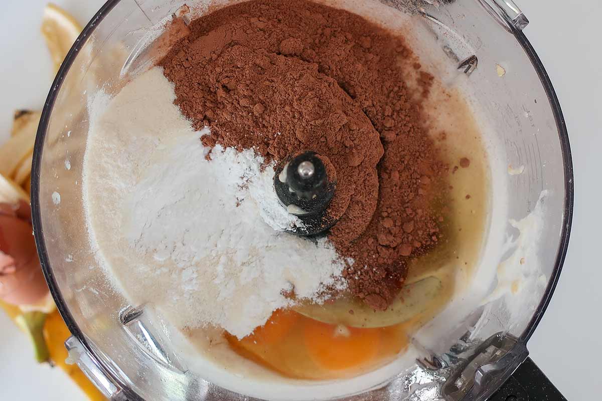 Shot of the powders , eggs and vanilla sitting on the banana cream in a food processor