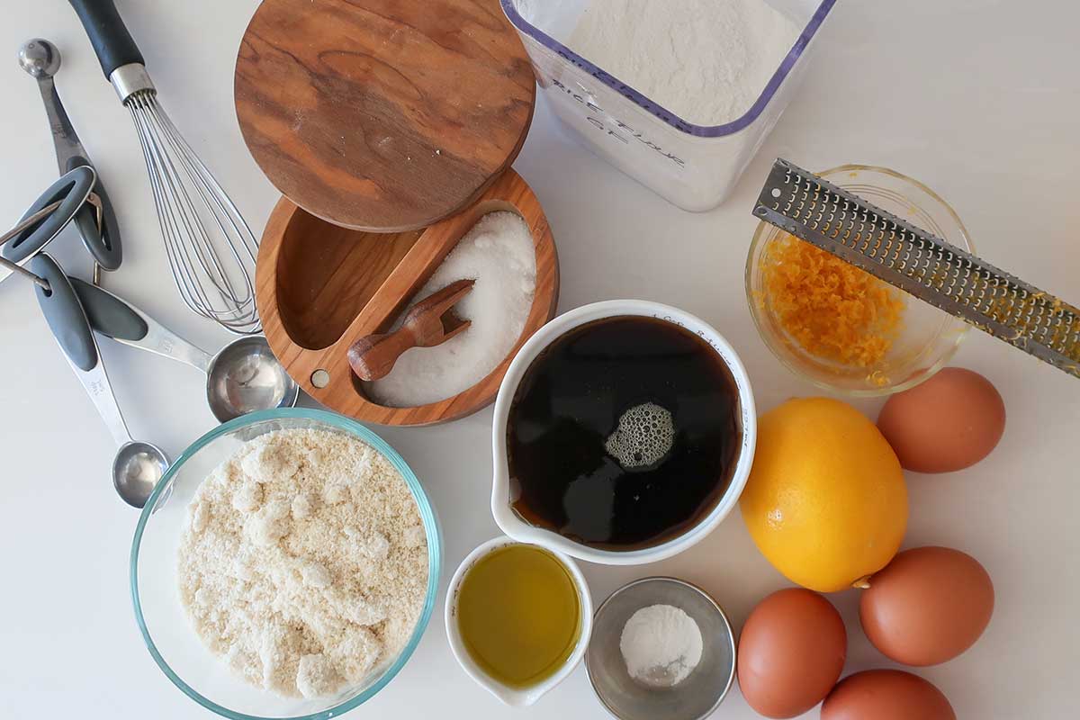 Ingredients for healthy maple lemon bars including almond flour, maple syrup, olive oil, eggs, lemon juice, and rice flour.