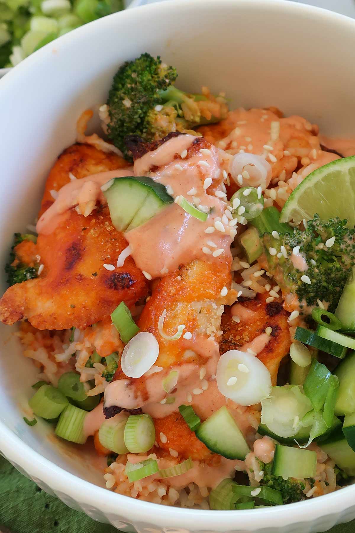 close up of bang bang chicken casserole with rice in a serving bowl with fresh toppings
