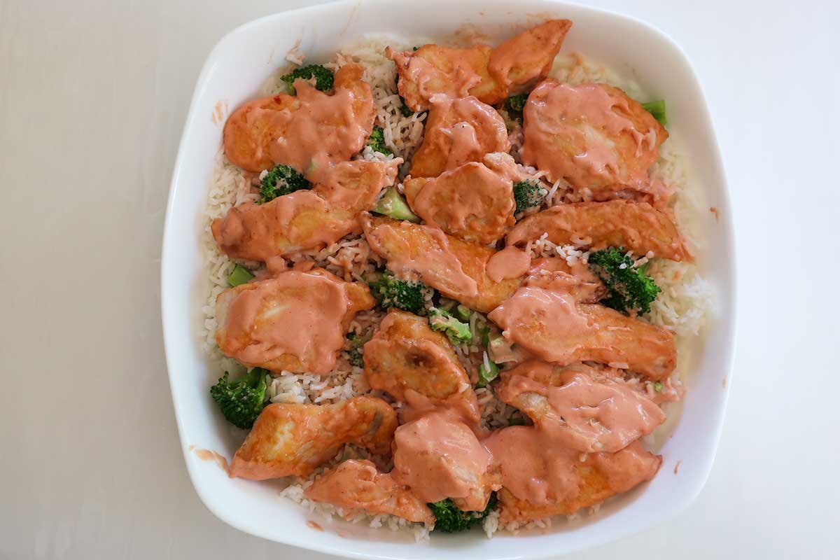 bang bang chicken over rice before baking in a casserole dish