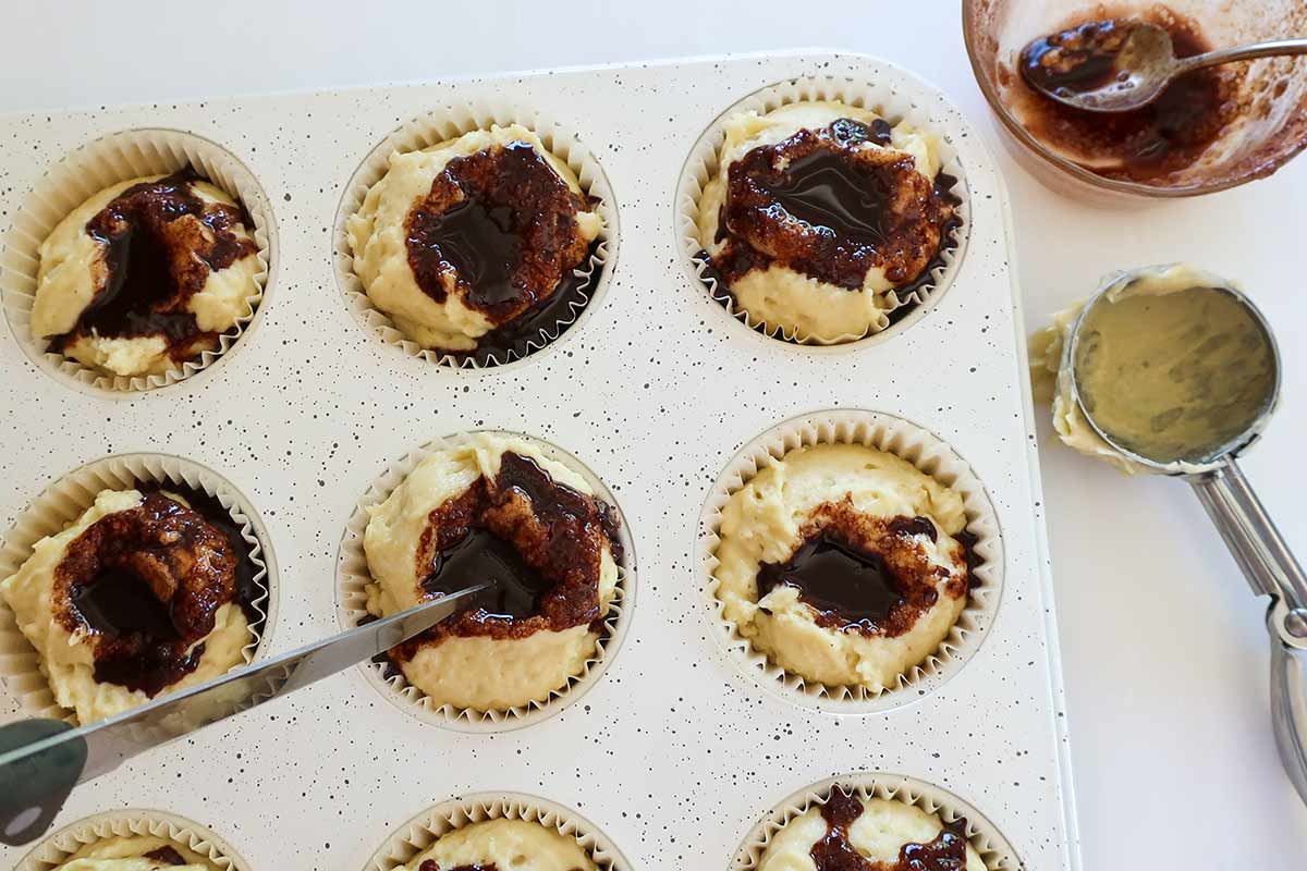 Adding the cinnamon butter swirl into the muffin batter before swirling in the pan