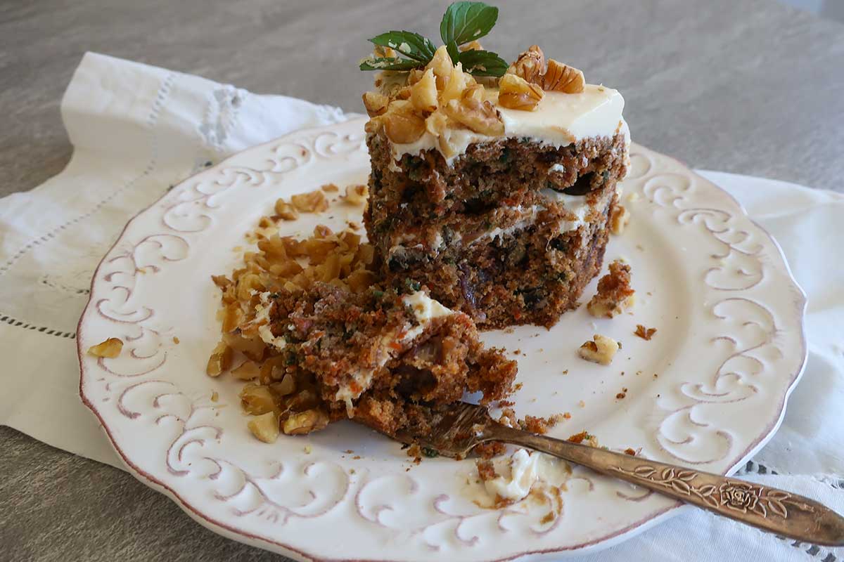 close-up of moist carrot cake with dates and walnuts on a fork