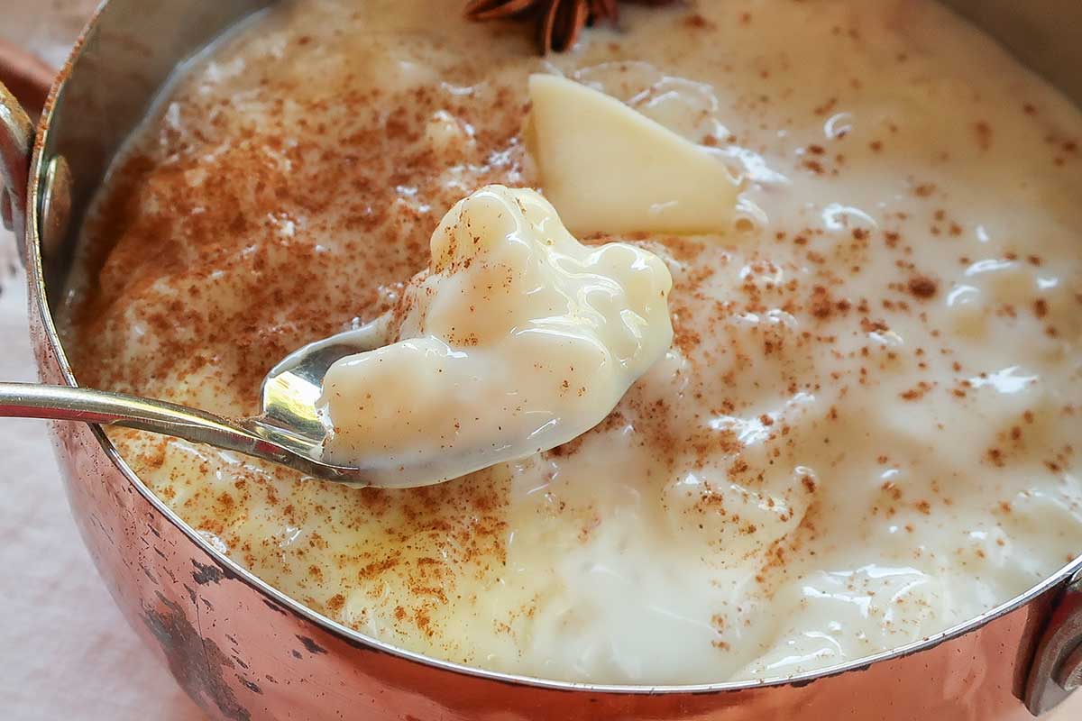close up of creamy rice pudding in a copper bowl topped with a melted dollop of butter