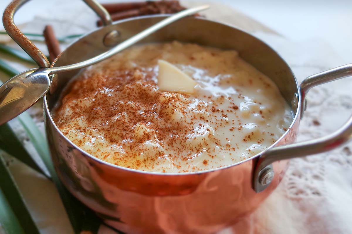 warm rice pudding in a rustic bowl topped with melted butter and cinnamon 
