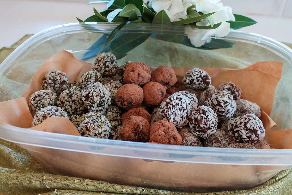 finished energy bites in a storage container lined with parchment paper ready for the fridge.