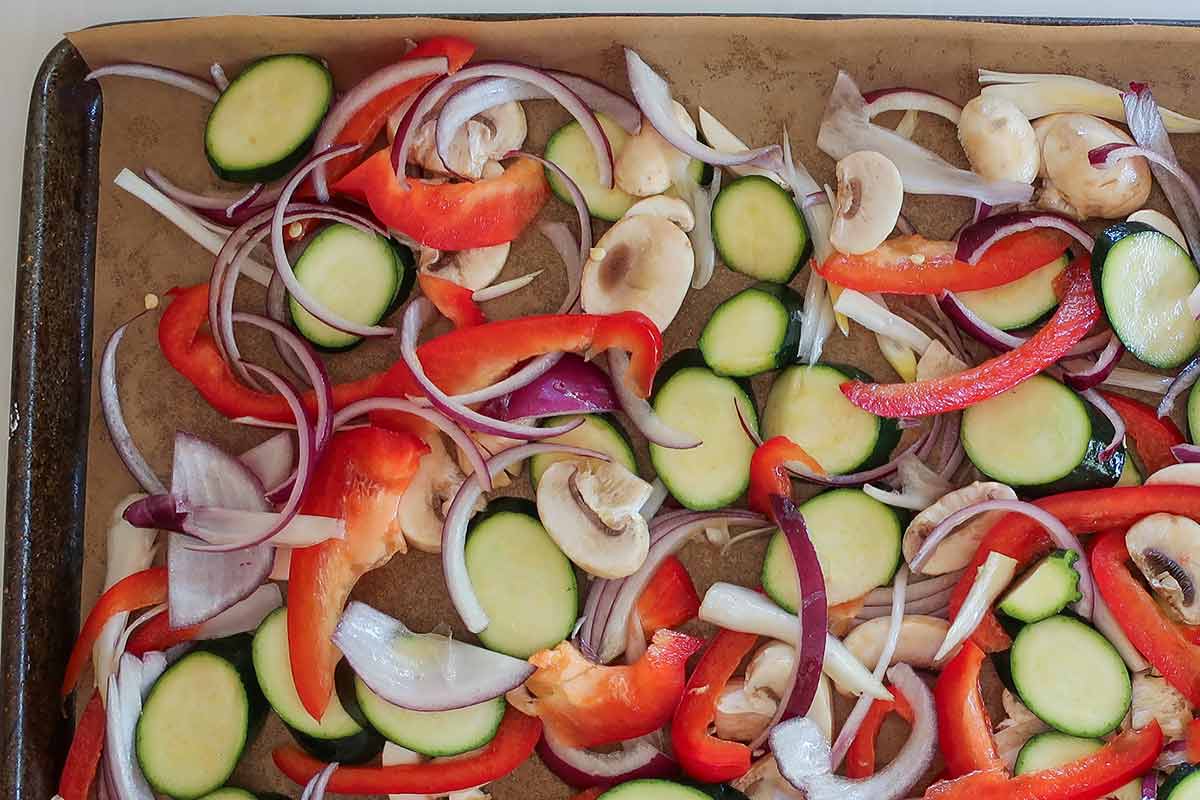 Roasted vegetables for gluten-free cast iron pizza including zucchini, mushrooms, red onion, & bell peppers,