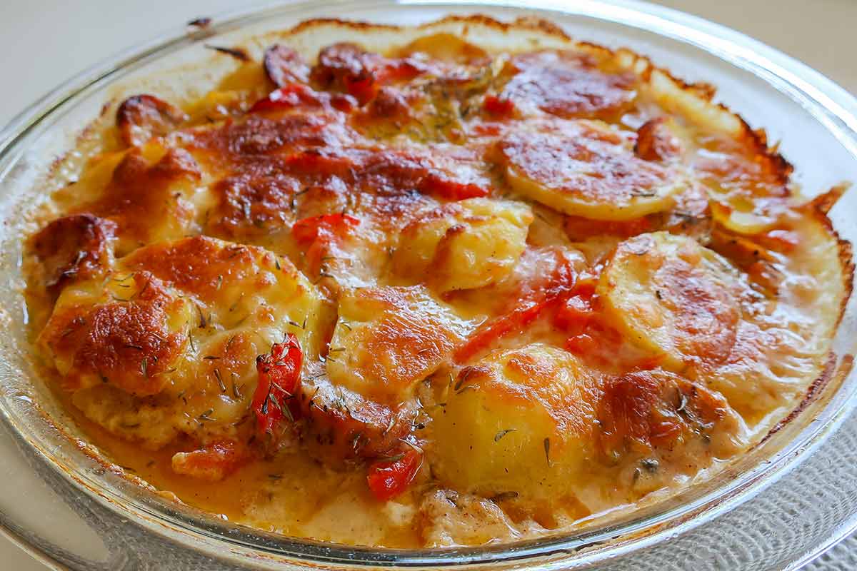 hot rustic cheesy sausage potato bake in a pie dish 