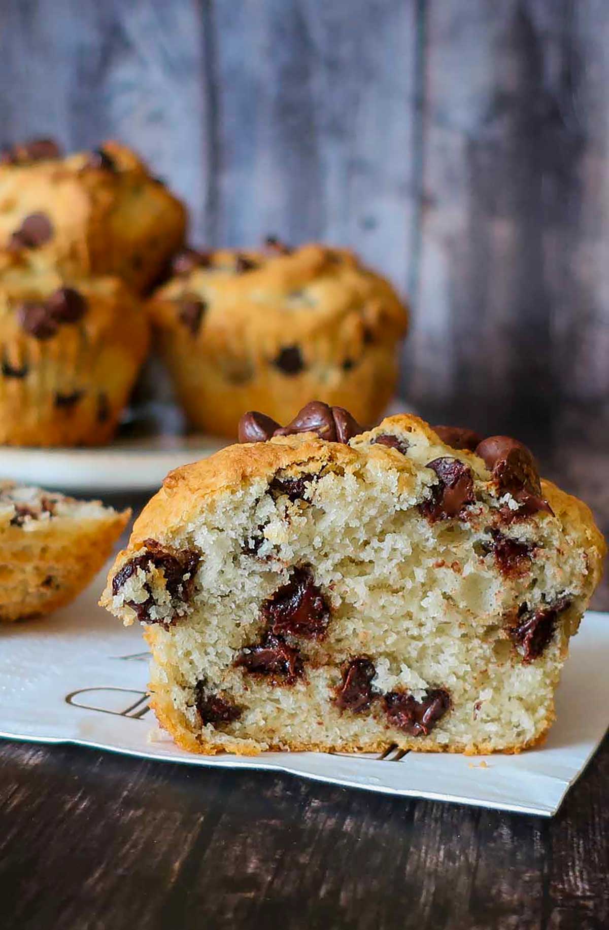 Gluten-free muffin with chocolate chips sliced in half showing a moist, even crumb on a wood cutting board