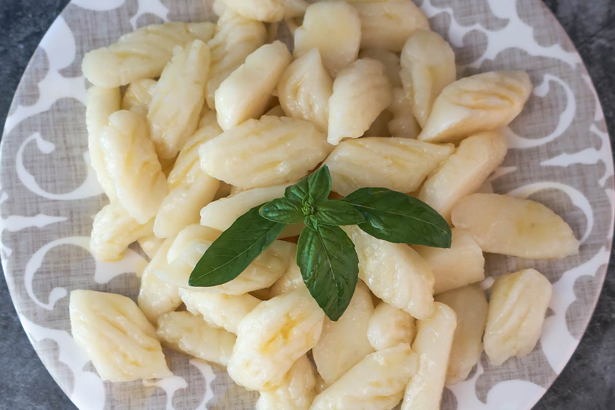 perfect texture of cooked grain-free, egg-free gnocchi on a plate topped with basil