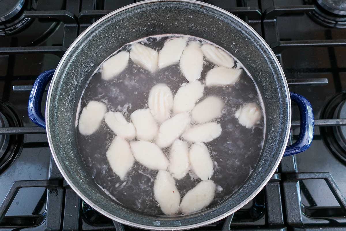 Gluten-free potato gnocchi boiling in a pot of hot water, showing the light and pillowy dumplings floating to the top surface.