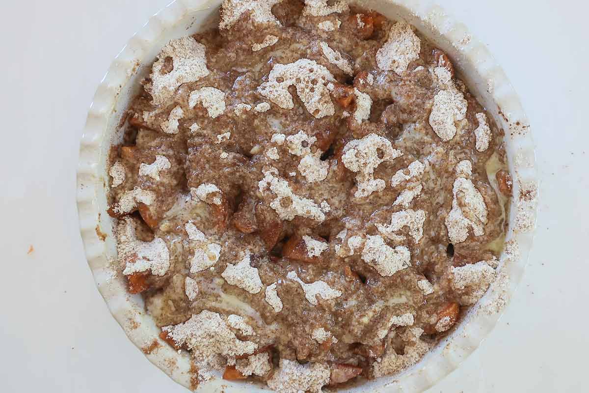 the two layers of apricots and flour blend is drizzled with melted butter in a deep pie dish